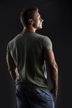 Handsome muscular fit young man's back on dark background
