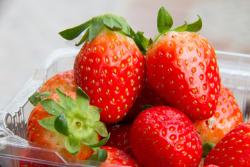 close up of fresh strawberries on the table and inside plastic b