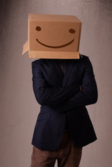 Young man gesturing with a cardboard box on his head with smiley