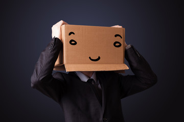 Businessman gesturing with a cardboard box on his head with smil