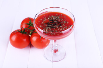Tomato juice in glass goblet and fresh tomatoes