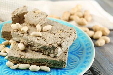 Sunflower halva with peanuts on plate, on wooden background