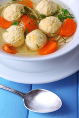 Soup with meatballs and noodles in bowl on wooden background