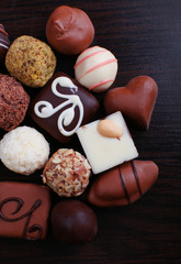 Assorted chocolates on the dark wooden smooth background