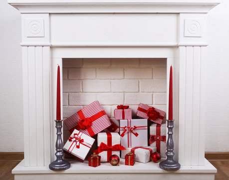 Fireplace with Christmas boxes and candles on wooden floor