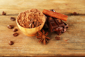 Bowl of cocoa with spices and coffee beans on wooden background