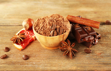 Bowl of cocoa with spices and coffee beans on wooden background