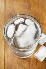 Summer cocktail with ice cubes on wooden table