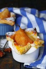 Small pear pies in cups, on wooden table
