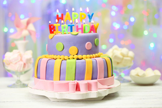 Delicious birthday cake on shiny light background