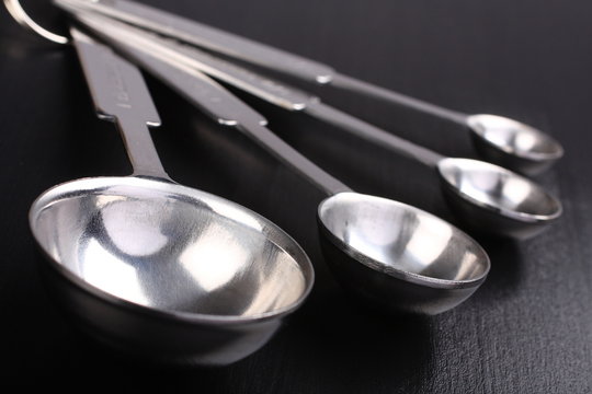 Empty metal measuring spoons on black background