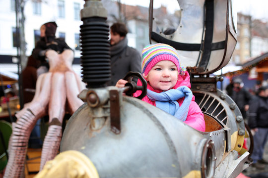 Cheerful toddler girl enjoying merry-go-round