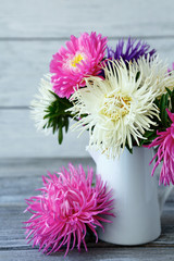 Fototapeta premium Fragrant asters in a jug on the boards