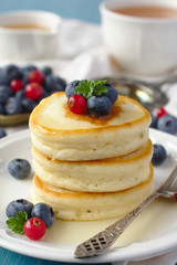 Stack of pancakes with fresh berries and honey