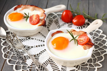 Fried egg with bacon and tomato in ceramic pan