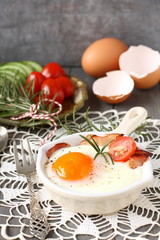 Fried egg with bacon in ceramic pan on wooden background