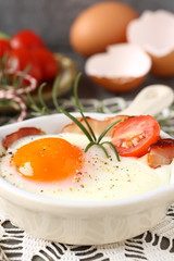 Fried egg with bacon in ceramic pan on wooden background