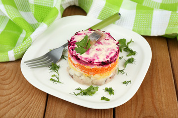 Russian herring salad on plate on wooden table background