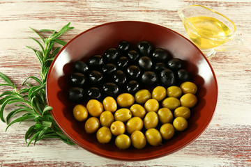 Black and green olives in bowl with branch