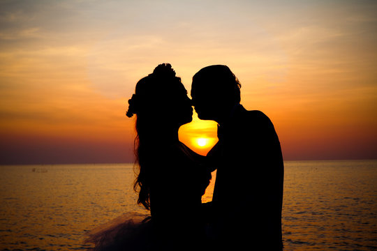 Love couple kissing silhouette at sunset.
