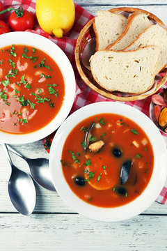 Tasty soups with  sea food in bowls on wooden background