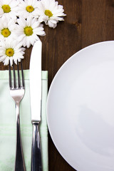 Cutlery and plate with flowers on wooden table