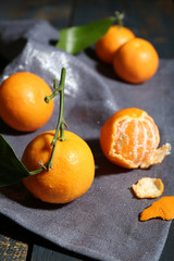 Juicy ripe tangerines with leaves on tablecloth