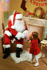 Santa Claus giving  present to  little cute girl near