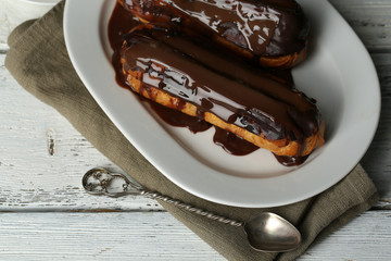 Tasty eclairs on wooden table, close up