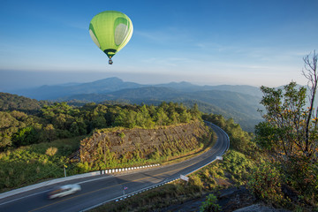 Hot air balloon over high mountain and road