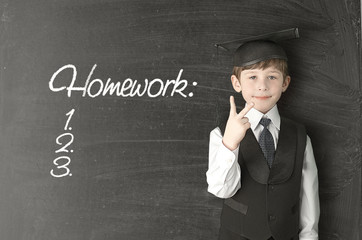 Cheerful little boy on blackboard. Looking at camera