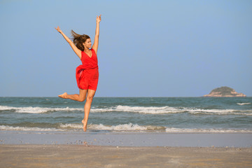 Young redhead girl jumping at the beach.
