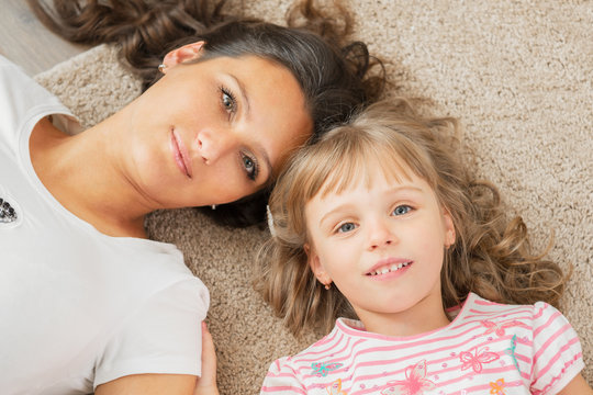 Mother and little daughter lying together on the floor