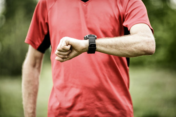 Runner looking at sport or smart watch checking pulse or gps
