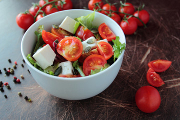 Fresh vegetable salad in a bowl on wooden kitchen table