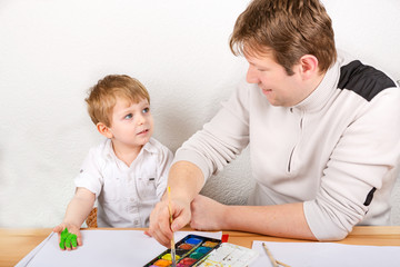 Little kid boy and his dad having fun with making handpaints