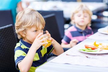 Two little kid boys having healthy breakfast in hotel restaurant