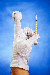 Burning birthday candle hold by finger puppet