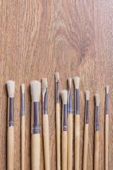 row of wooden paint brushes on table background