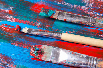 brushes and acrylic paint background with blue and red strokes