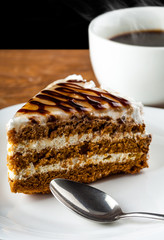 piece of chocolate cake on a plate with a spoon and black coffee