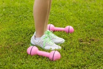 Woman with dumbbells on grass at park