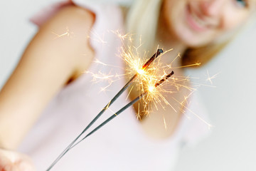 smiling woman holding sparklers in her hand