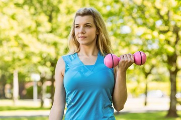 Fit blonde lifting dumbbells in the park