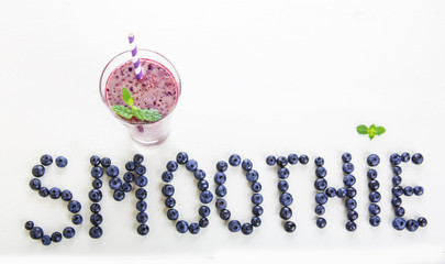 Blueberry smoothie in a glass jar with a straw and sprig of mint