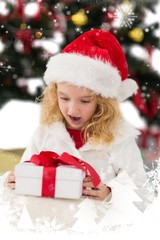 Composite image of festive little girl looking at gift