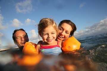 Family swimming in sea at sunset