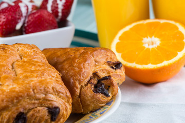 FReshly baked croissant with chocolate bits and orange juice
