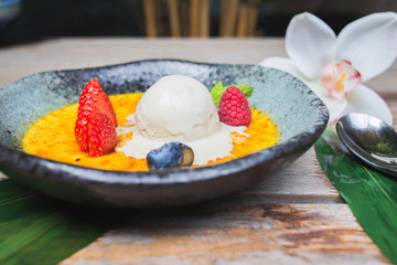 scoop of ice cream on a plate with fresh berries and creme