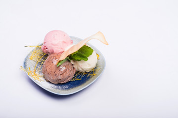 Three scoops of chocolate, strawberry and vanilla ice cream in